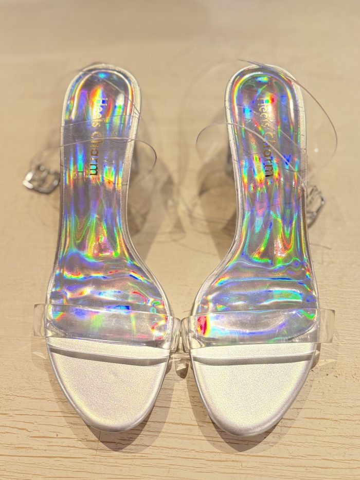 Iridescent slide heels with a holographic finish and a clear strap