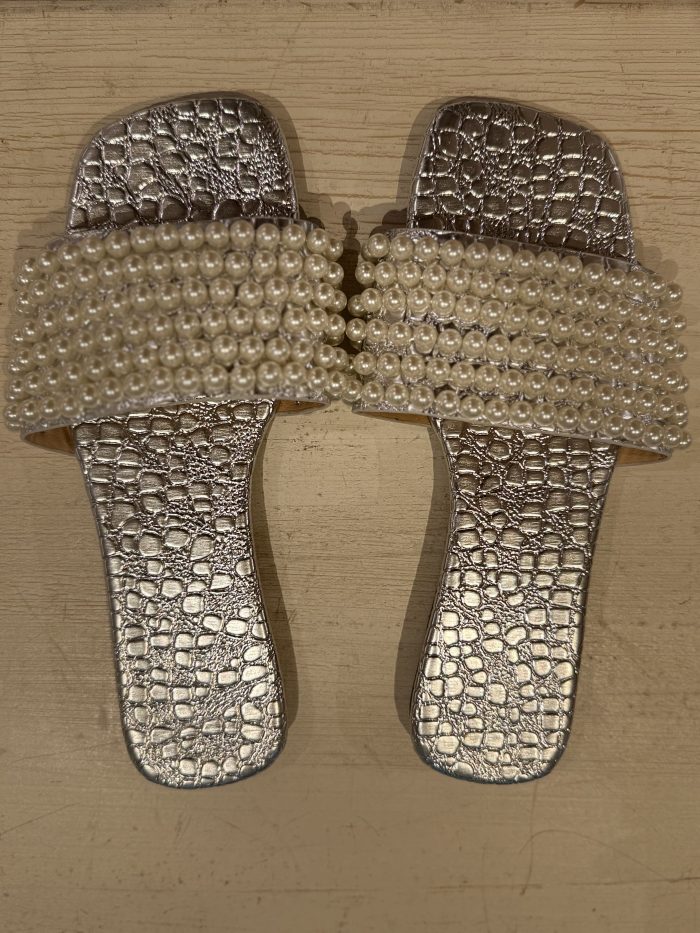 A pair of elegant silver sandals with a crocodile-textured design and pearl-embellished straps